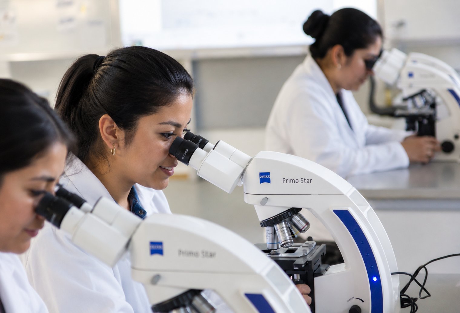 Alumnas universitarias observando muestras en microscopios ZEISS Primo Star